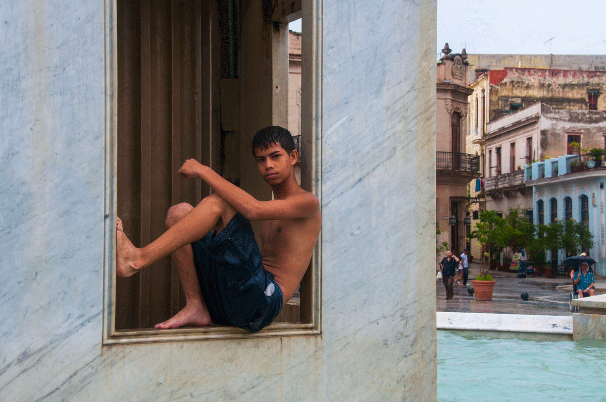 Young man sitting in a window frame.